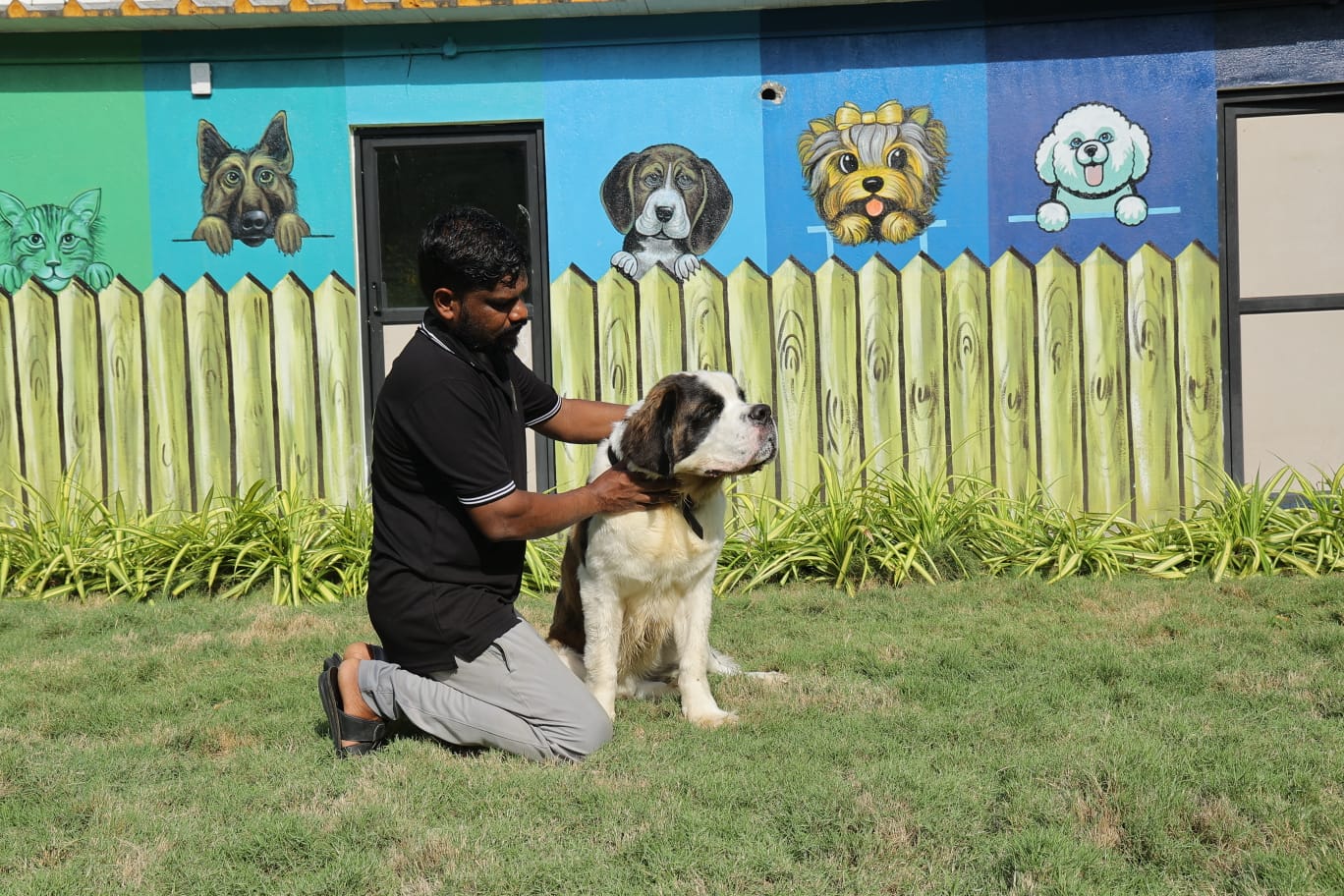 Staff with dog in front of the resort mural